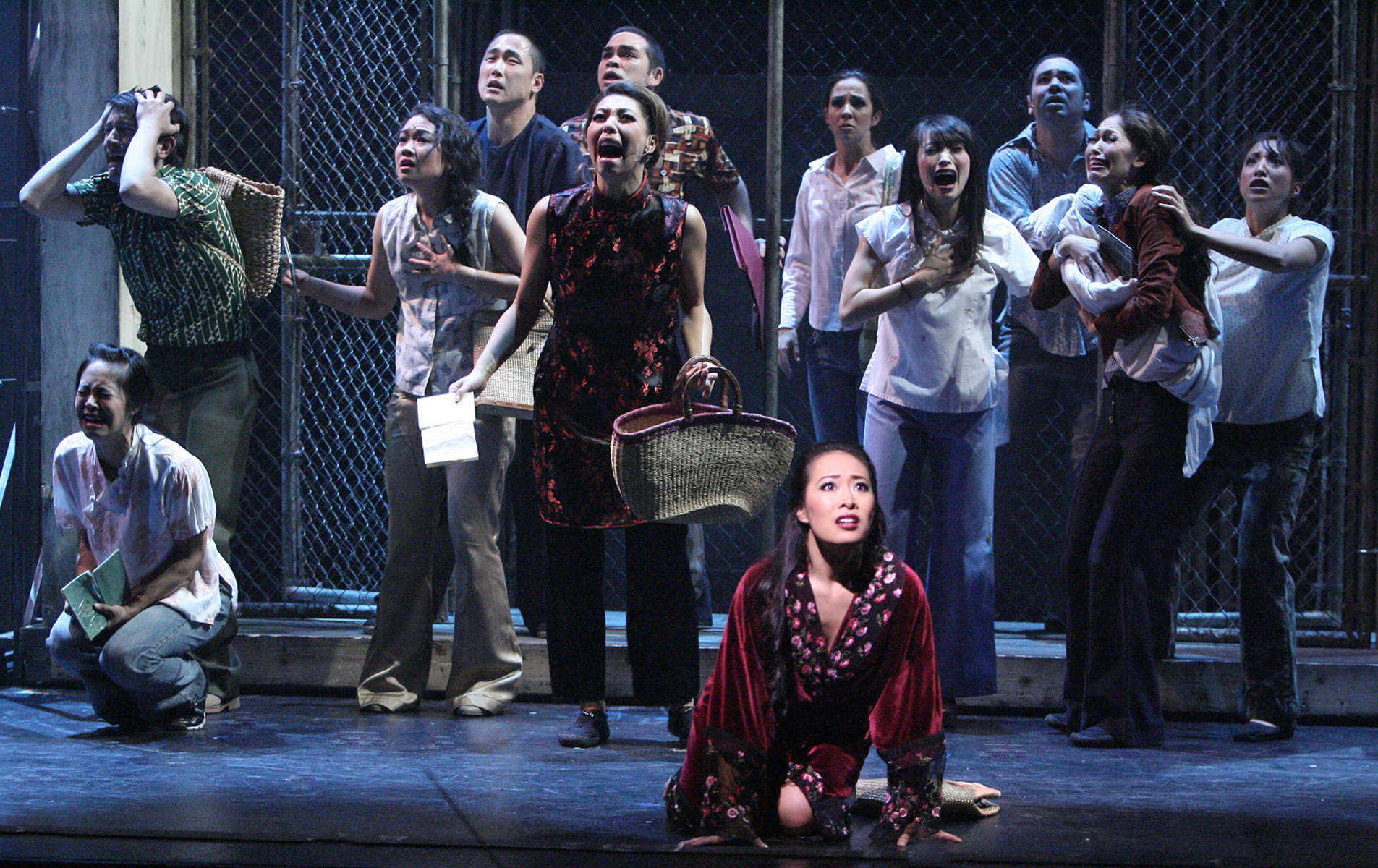 Kim and the ensemble watch as a helicopter departs without them in Miss Saigon.
