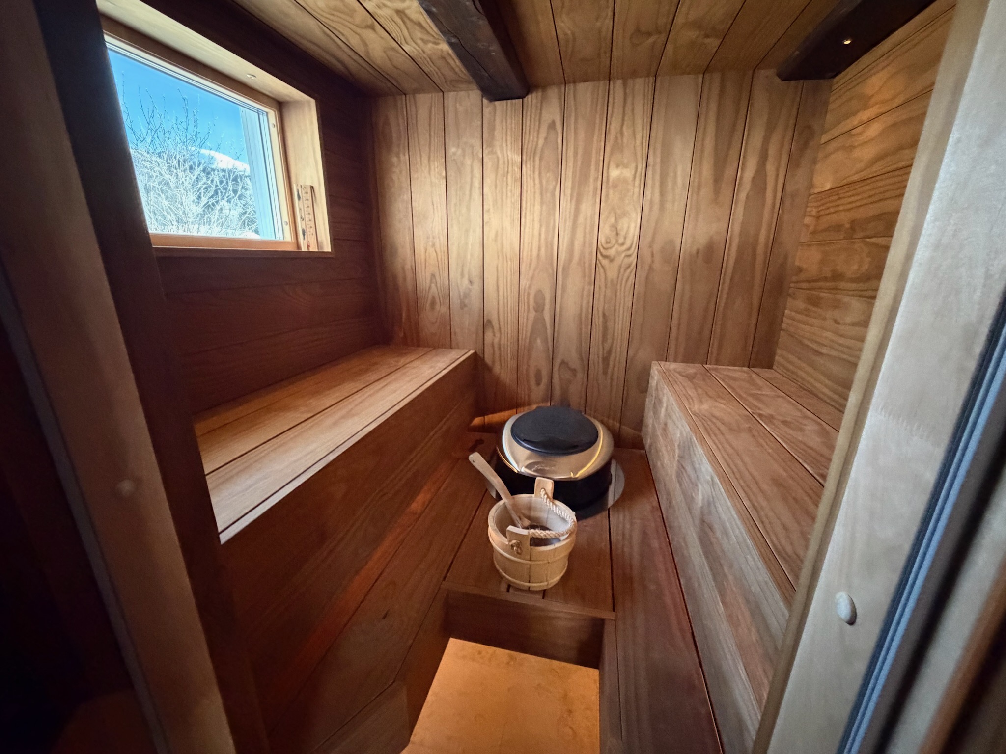 Sauna interior with wooden bucket and snowy window view