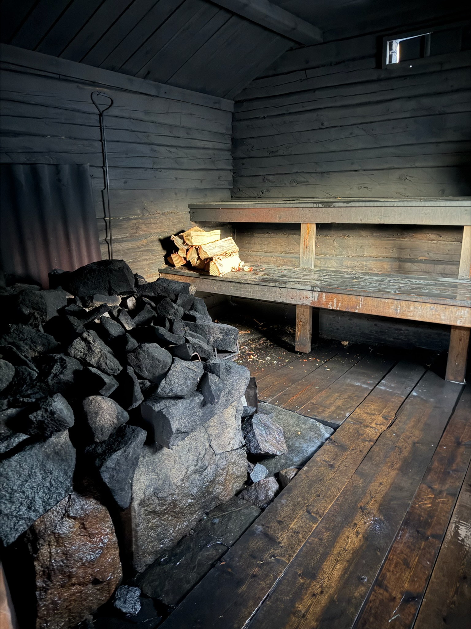 Traditional smoke sauna interior with rocks and firewood