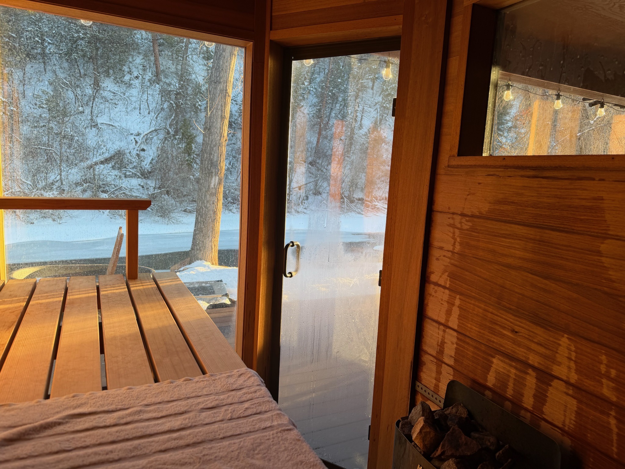 View from inside a sauna looking out to a snowy Nordic forest