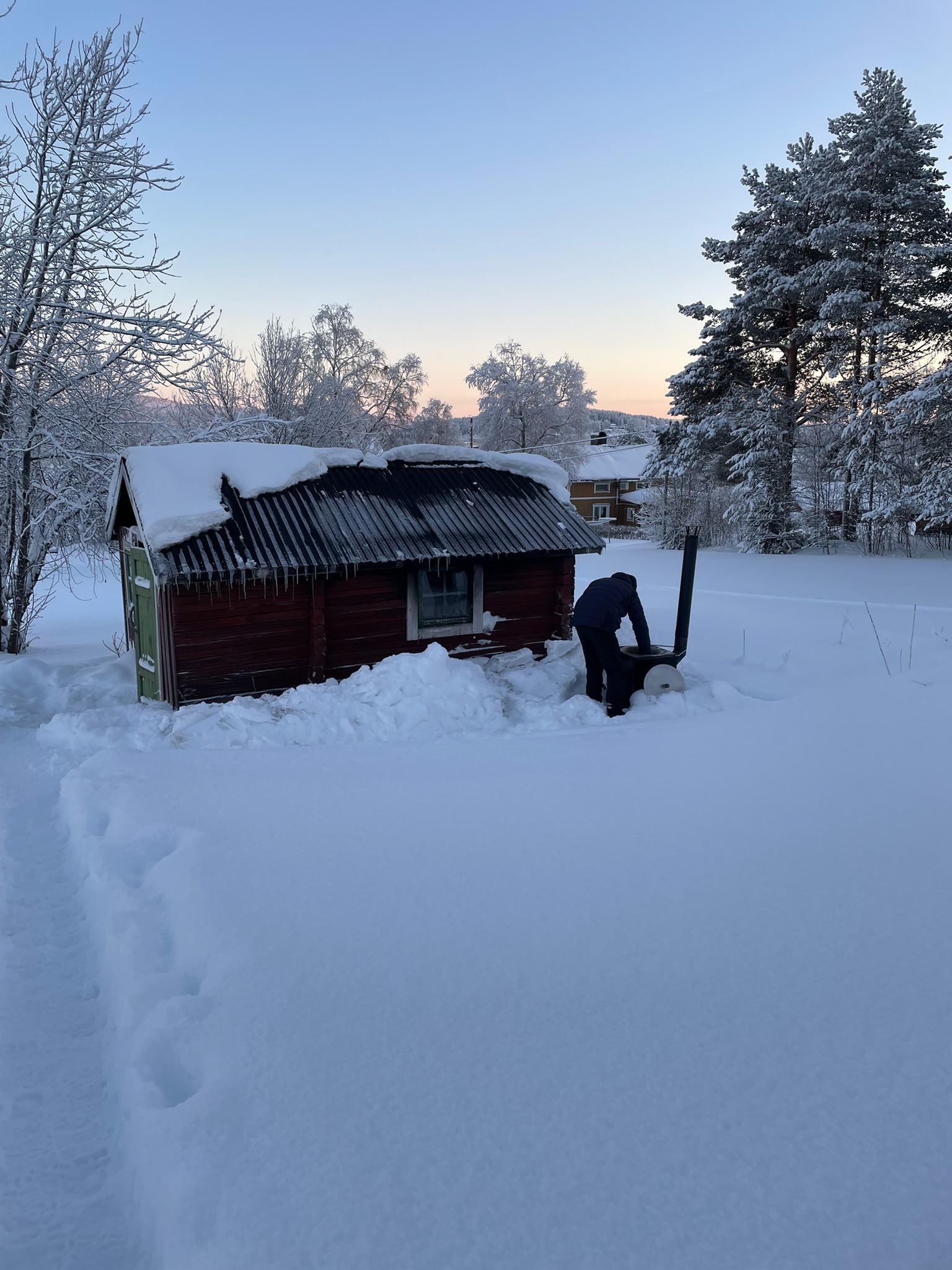 Traditional Swedish red cabin buried in deep winter snow