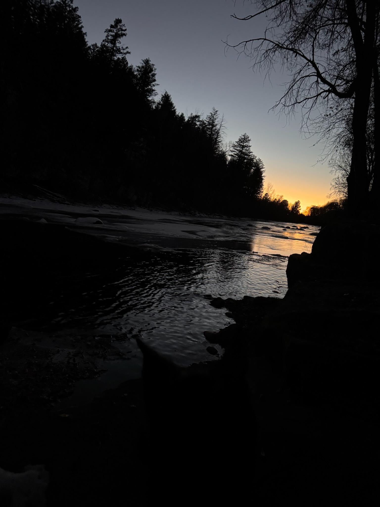 River at sunset silhouette through Nordic forest