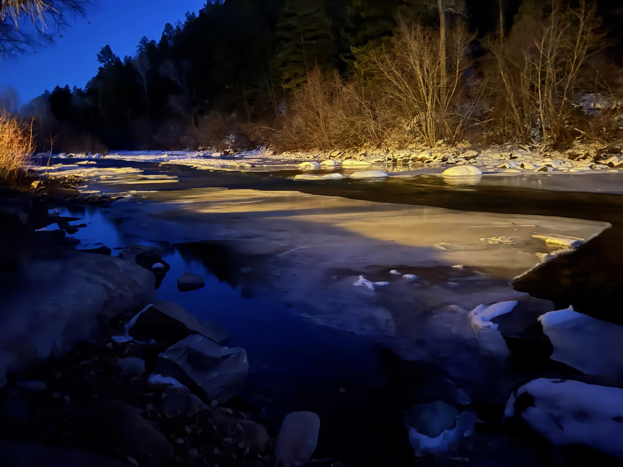 Icy river at night with warm and cold light reflections