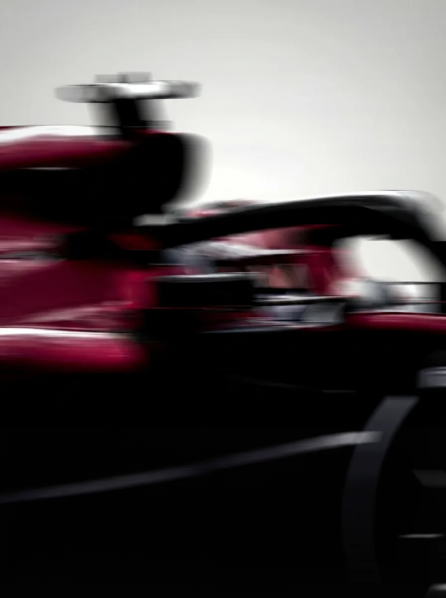 Formula One car in motion, red and dark against a blurred background