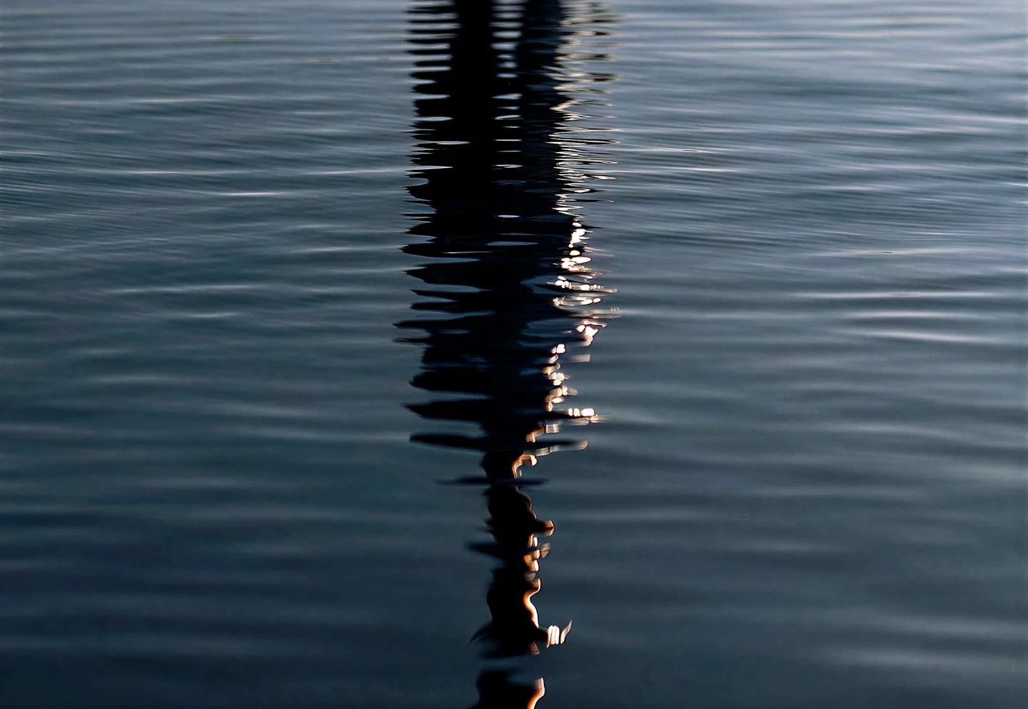 A figure reflected in still, dark water