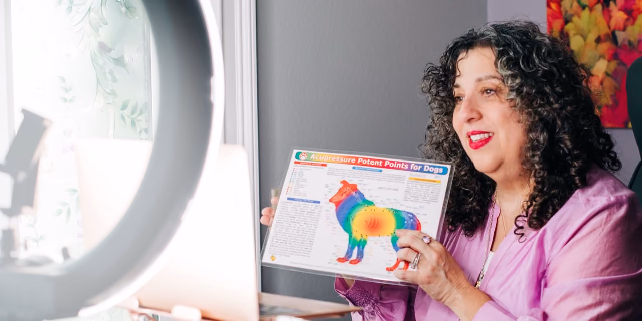 Kara holding chart showing acupressure points on a dog's body while smiling.