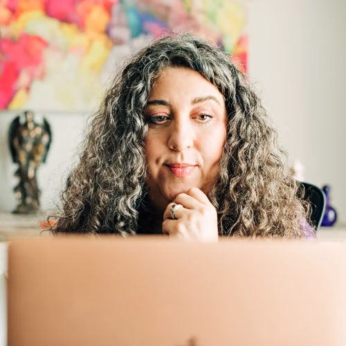 Kara concentrating on a laptop with colorful artwork in the background.
