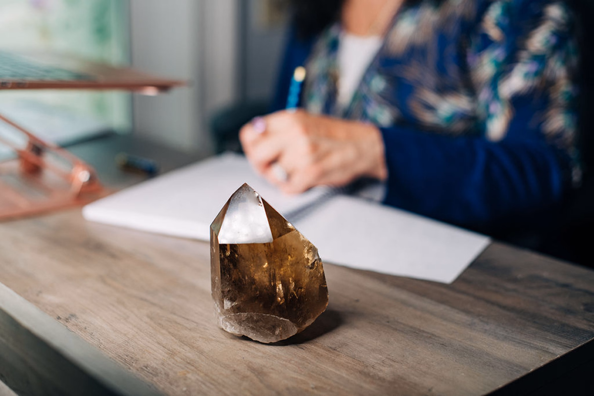 Crystal sitting on Kara’s desk while she writes