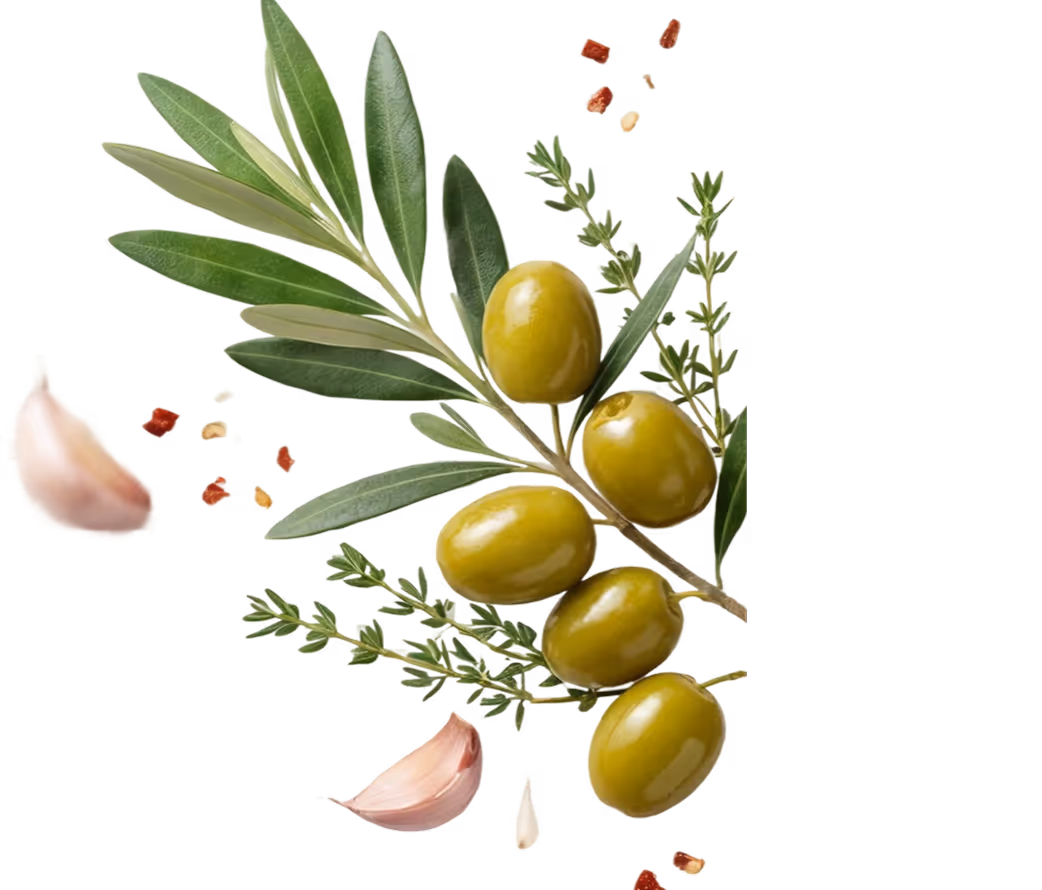 Branch with green olives, olive leaves, garlic cloves, and scattered red pepper flakes and herbs.
