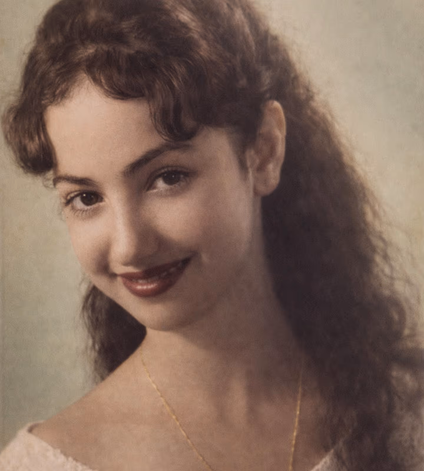 Young woman smiling. Dark long curly hair, dark eyes, faded old image.