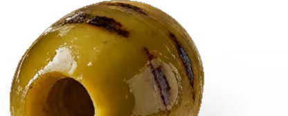 Close-up of a green olive with pits visible inside and dark spots on its surface.