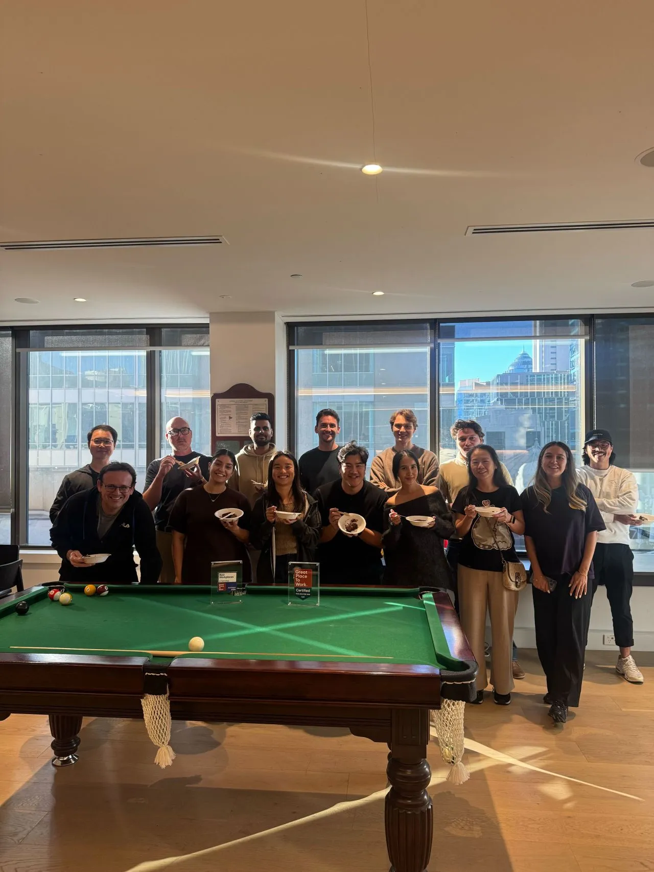 CORTO team gathered around a pool table during a company office celebration.