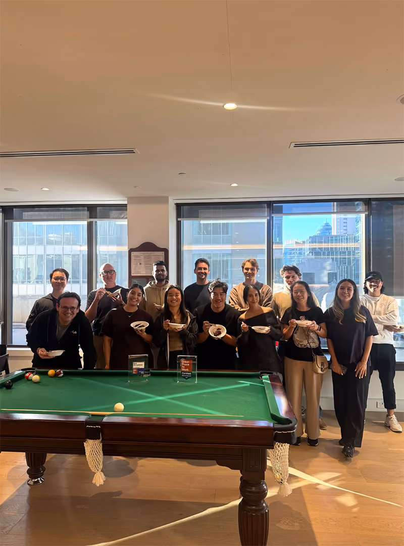 CORTO team gathered around a pool table during a company office celebration.