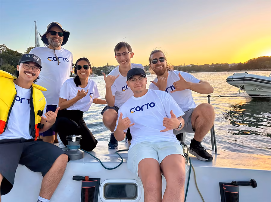 CORTO team members posing on a sailboat at sunset on Sydney Harbour.