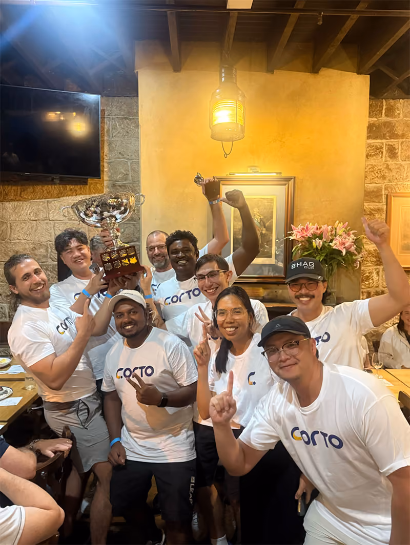 CORTO team celebrating holding the BHAG Cup trophy at a team dinner.