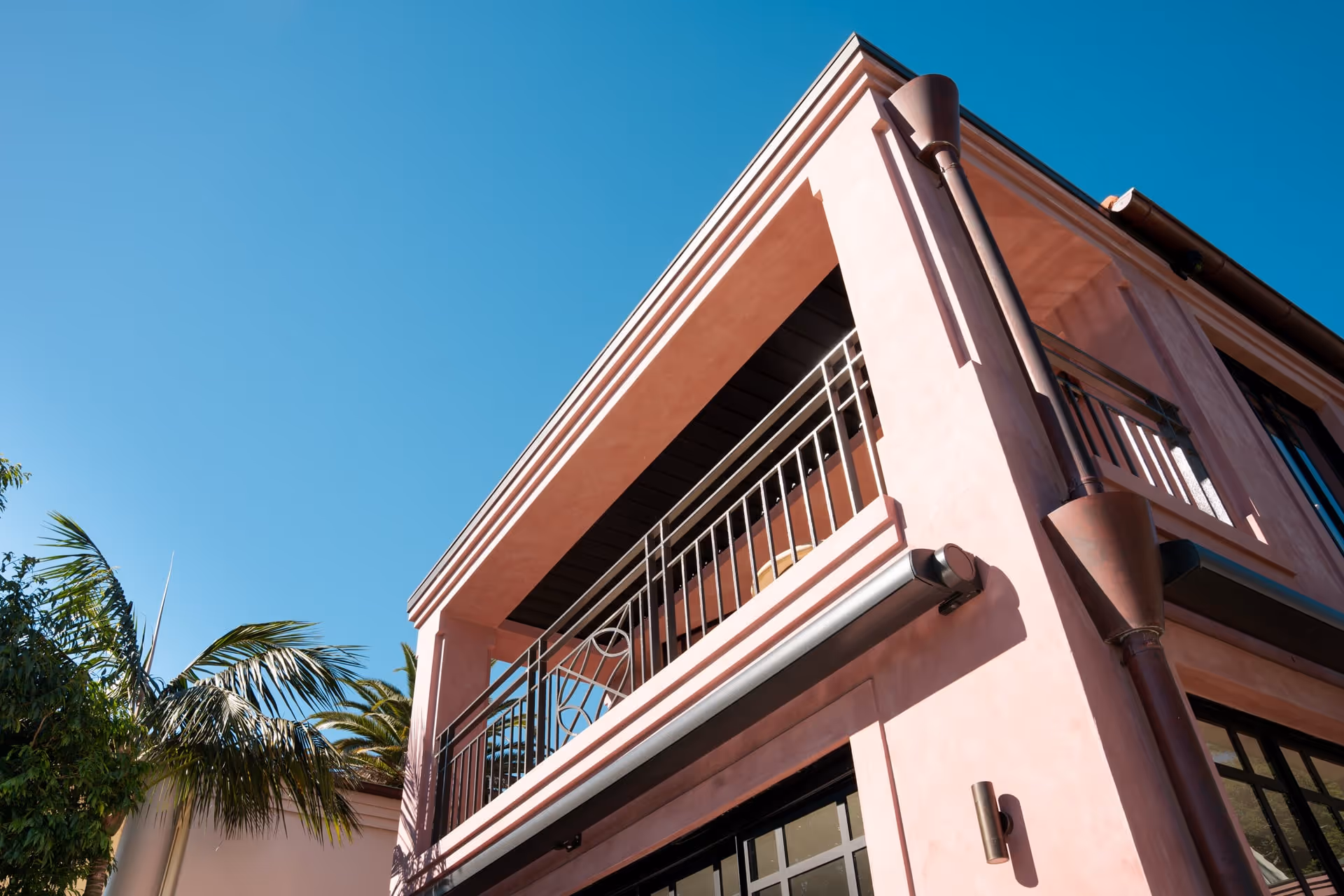 Exterior of a Sydneyside Contracting residential build with a rendered facade and balcony under a clear blue sky
