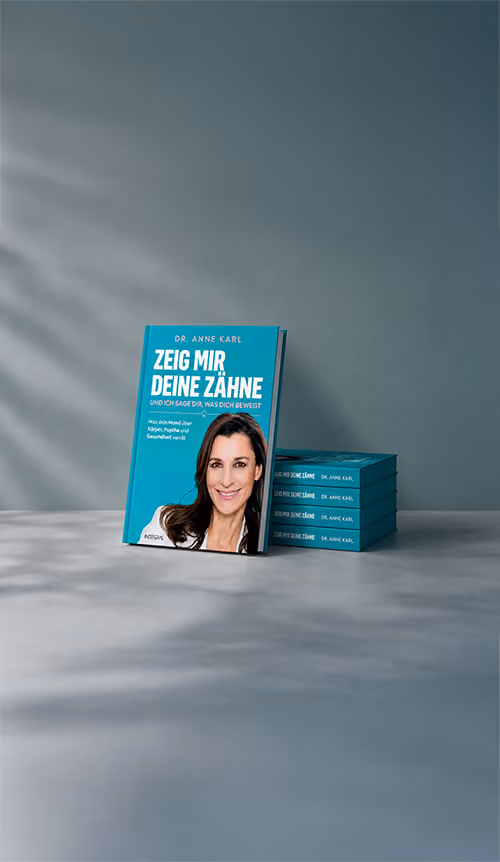 Buch mit dem Titel "Zeig mir deine Zähne" von Dr. Anne Karl, daneben ein Stapel gleicher Bücher.