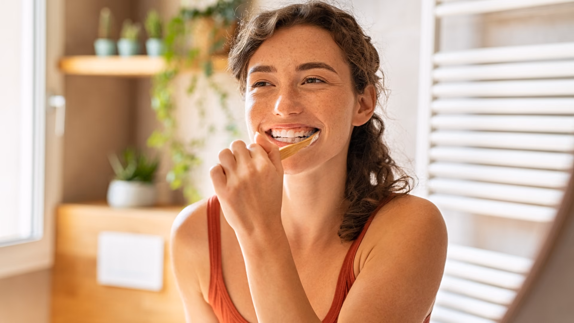 Woman brushing her teeth with a bamboo toothbrush as part of a natural oral care routine