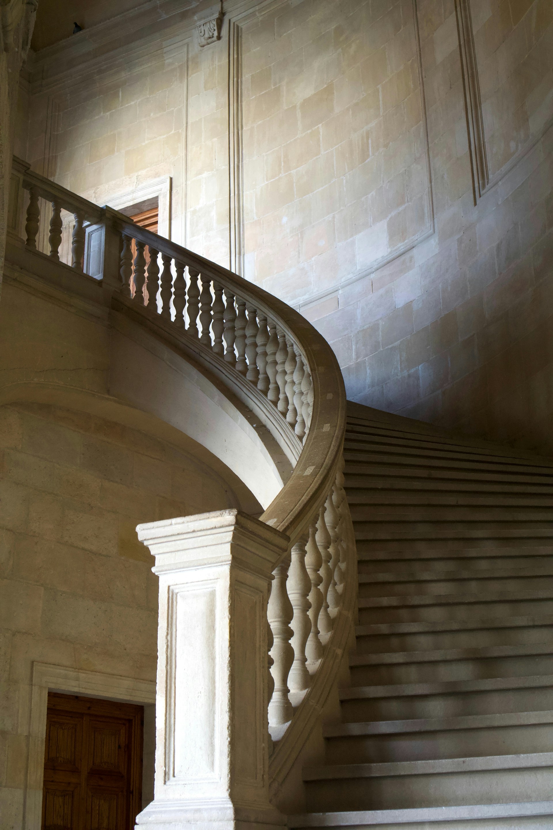 Worker in yellow safety vest and helmet is on ornate marble staircase in a decorative building interior.