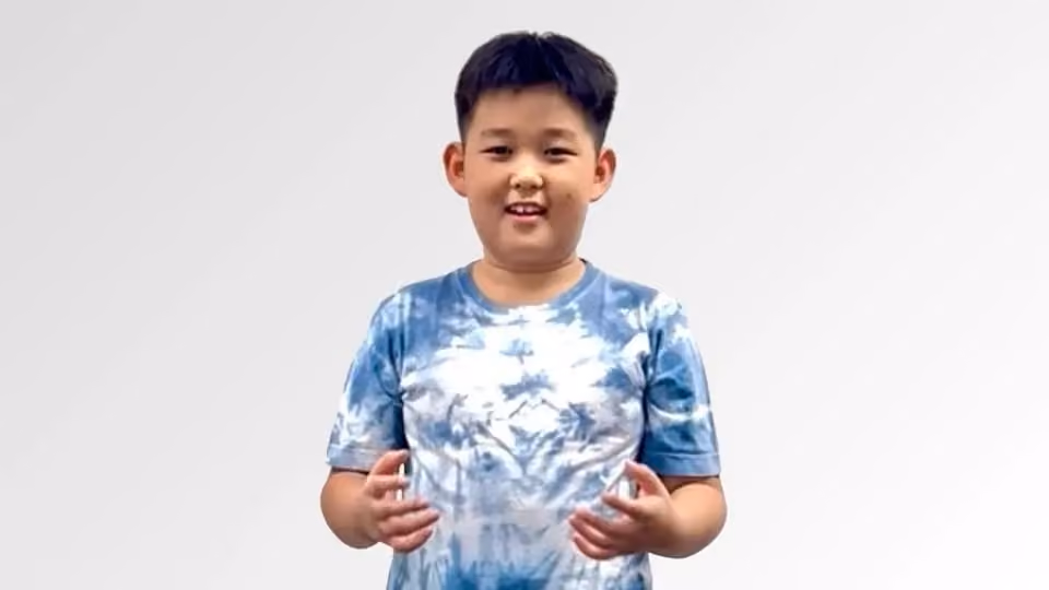 Young boy smiling wearing a blue and white tie-dye t-shirt against a plain white background.