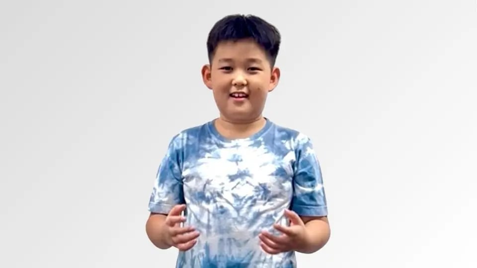 Young boy smiling wearing a blue and white tie-dye t-shirt against a plain white background.