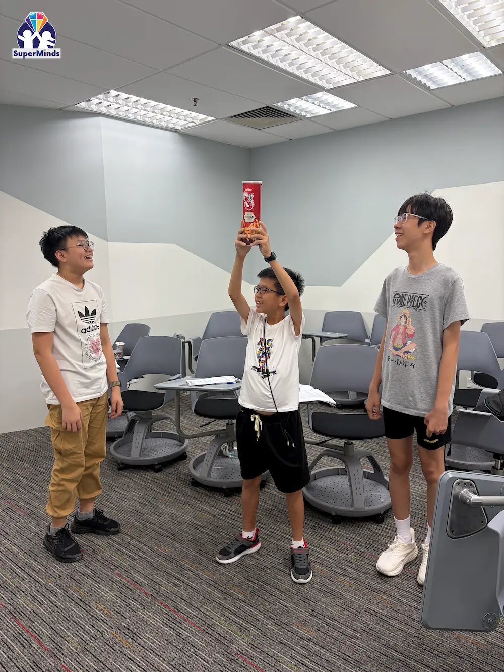 Smiling child gesturing excitedly between two seated adults in a bright room.