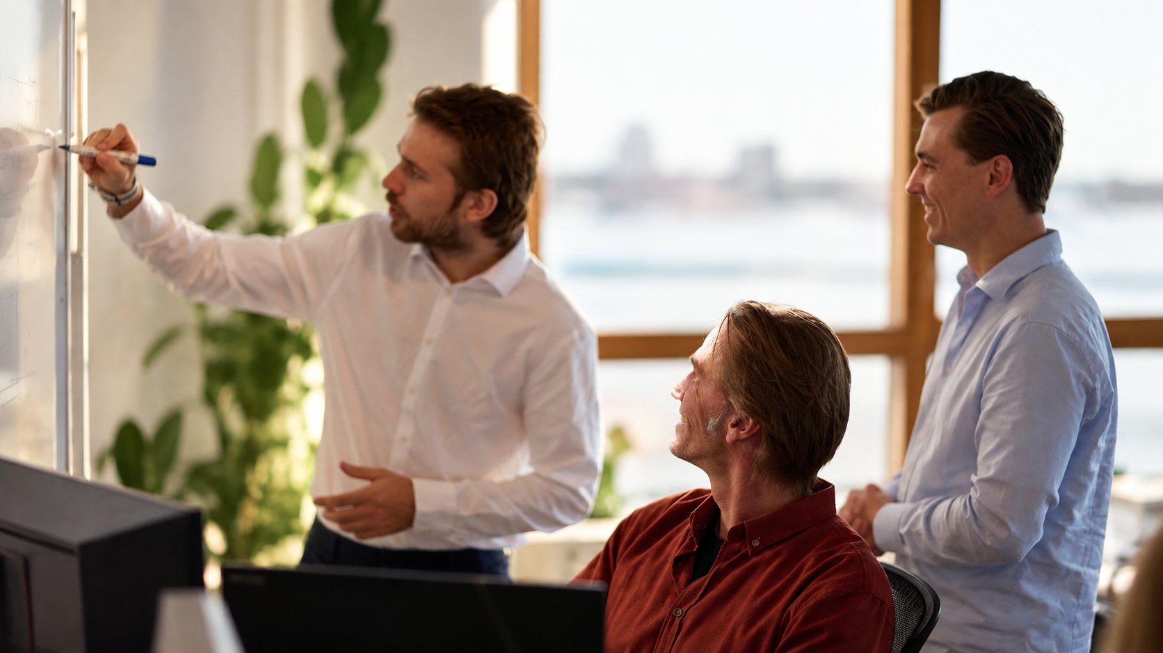 Drie collega's werken samen aan een whiteboard tijdens een ambassadorsessie