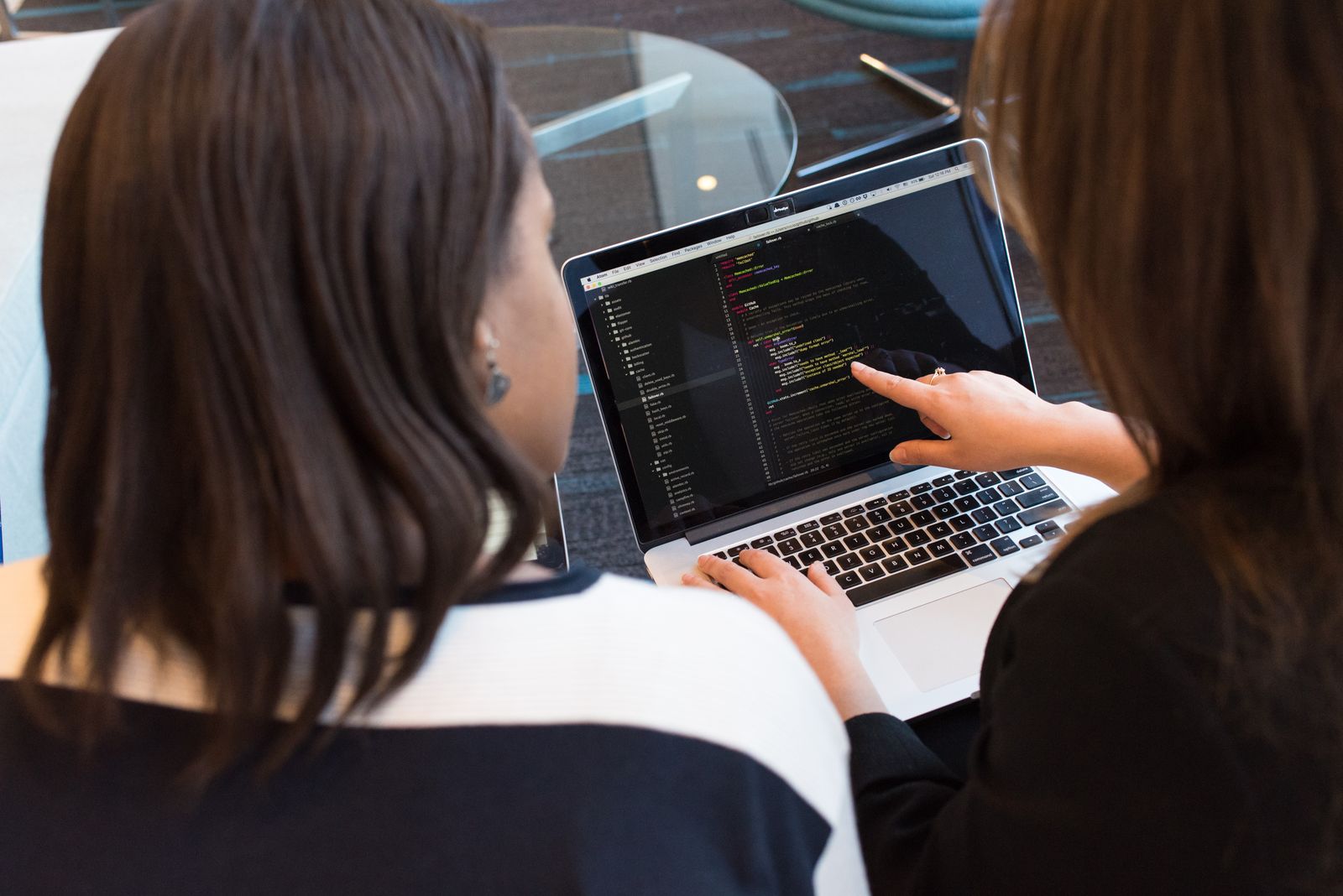 Twee developers werken samen aan code op een laptop