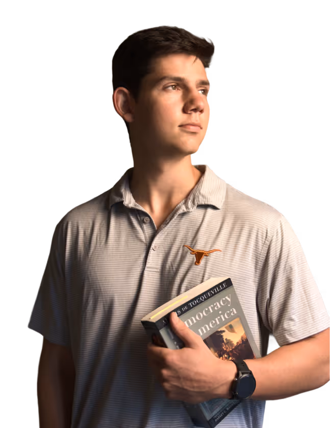 Young man in a striped polo holds a book titled Democracy in America, looking to the side.
