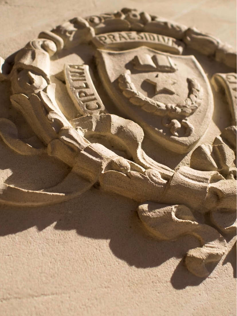 Stone emblem carved on a wall with a shield, wreath, and Latin inscriptions PRAESIDIUM and VIGILANTIA.