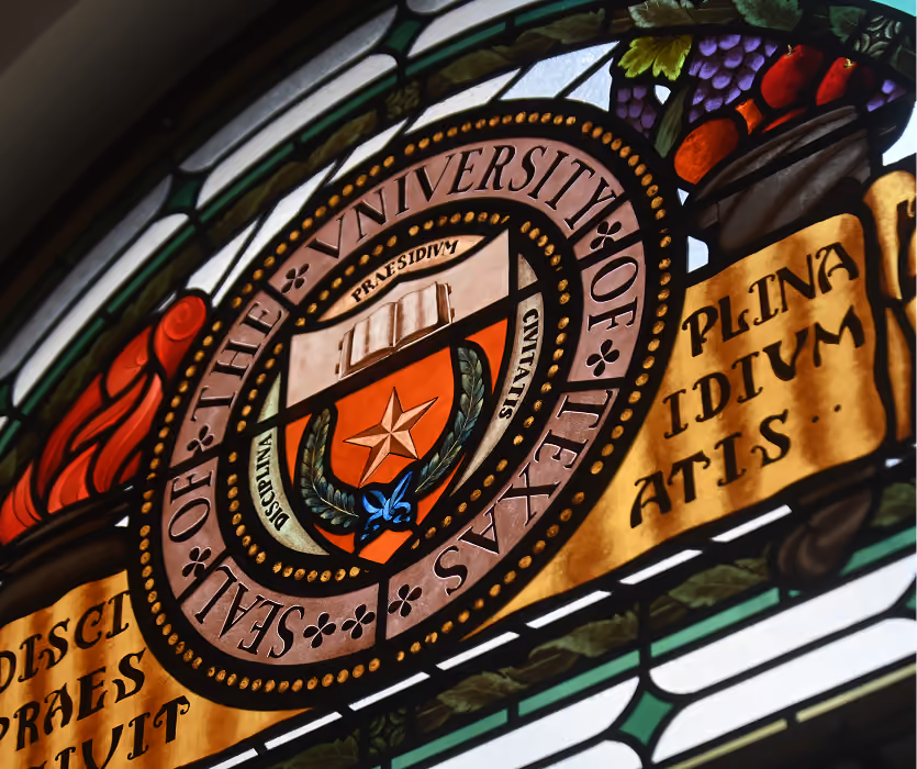 Stained glass featuring the seal of The University of Texas with Latin text and decorative elements.