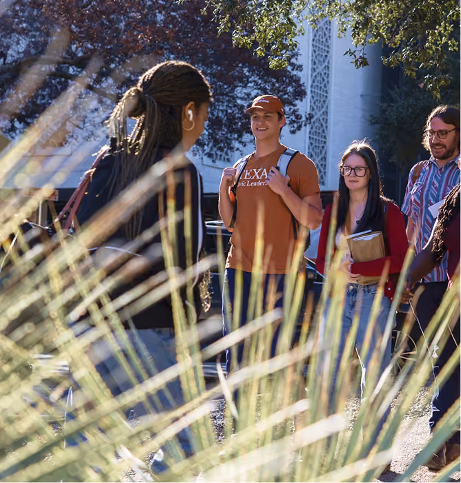 Group of diverse students talking and walking outdoors on a sunny university campus.