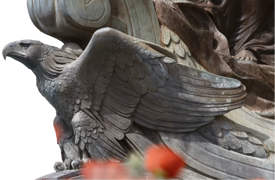 Detailed stone sculpture of an eagle with spread wings and carved feathers.