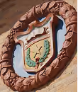 Circular emblem with a heart and tree design on a stone wall.