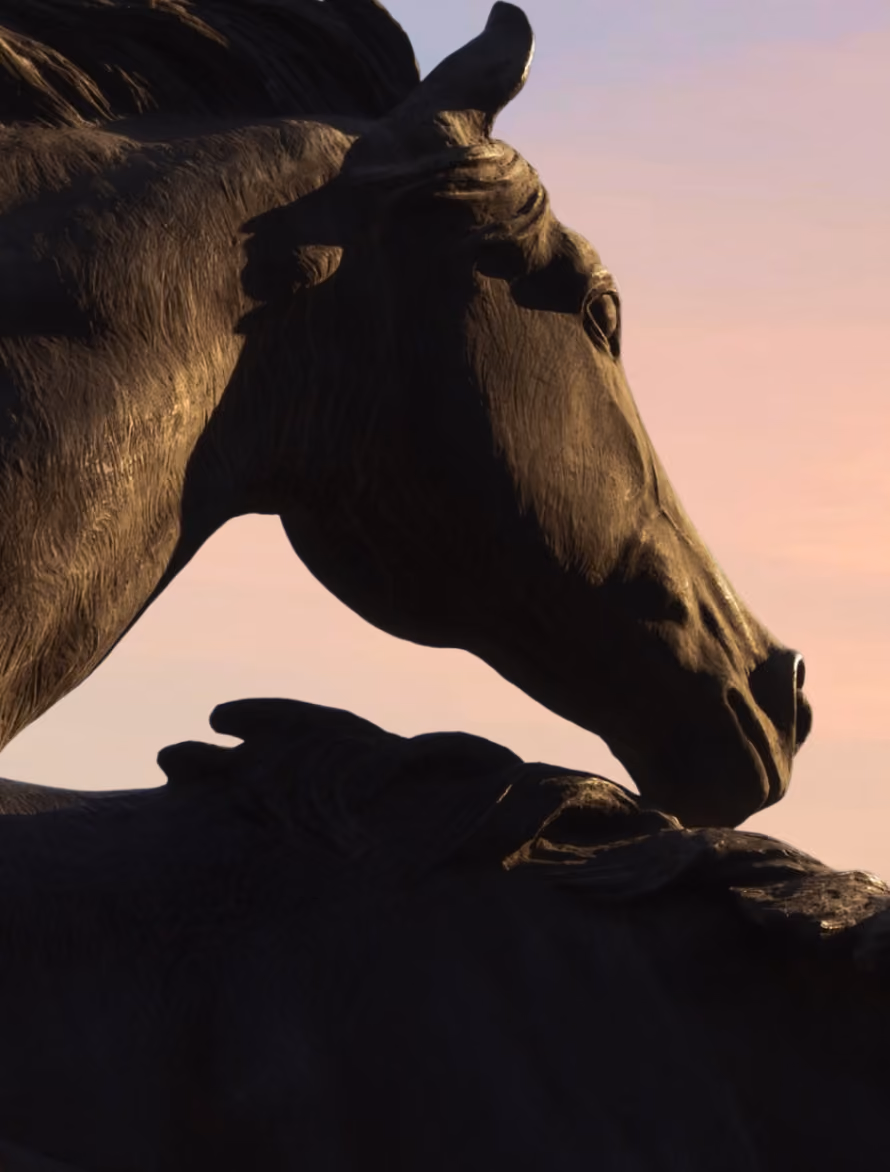 Close-up of cow statues with textured detail against a soft pink and blue sky at sunset.
