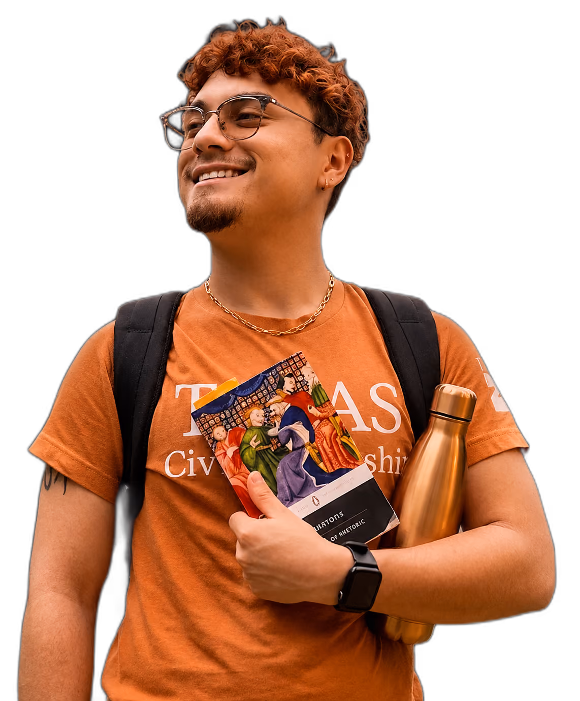 Smiling young man wearing glasses and orange shirt holding a book and a gold water bottle.