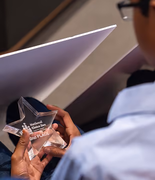 Person holding a clear star-shaped award for 2nd place in National Spelling Bee.