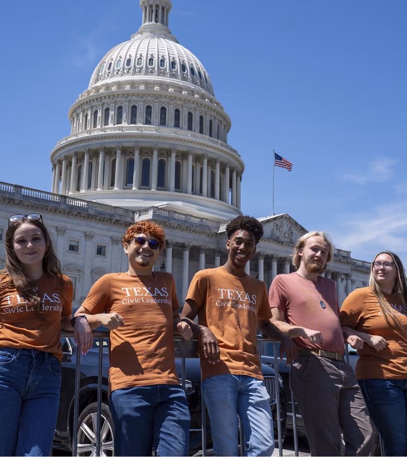 Five young adults wearing Texas Civic Leadership shirts pose in front of the U.S. Capitol building.