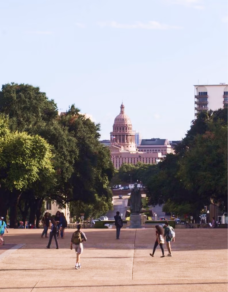 People walking along a tree-lined path with a domed government building in the background.