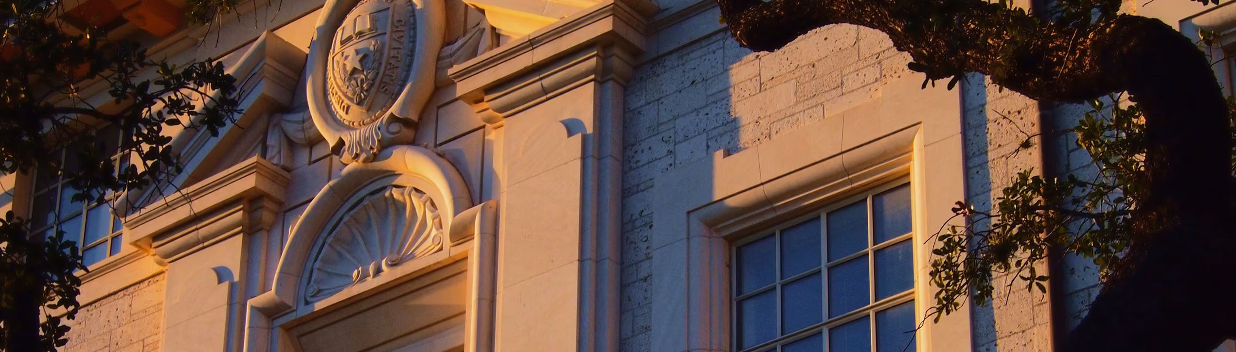 Close-up of a stone building facade with ornate architectural details and a shield emblem.