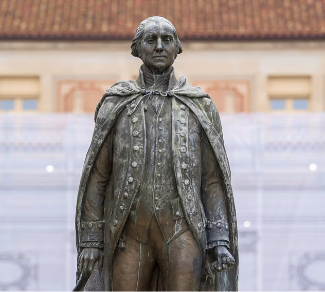 Bronze statue of a historical figure wearing a buttoned coat and cape, standing upright.