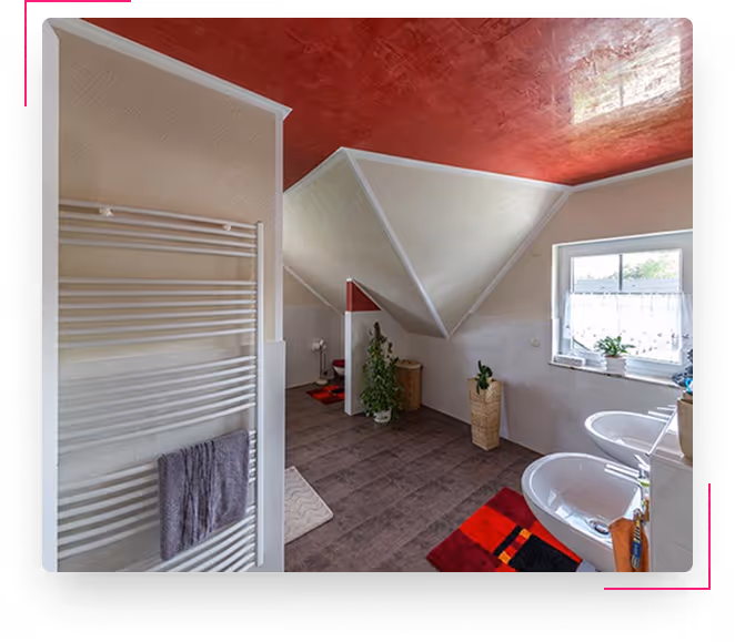 Badezimmer mit roter Decke, weißem Handtuchheizkörper, zwei Waschbecken und Pflanzen an den Schrägwänden.