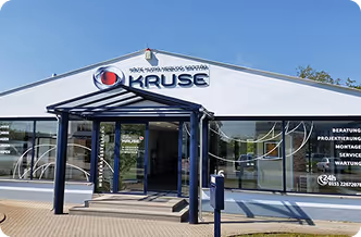 Eingang zu einem modernen Firmengebäude mit Kruse-Logo und Serviceangeboten am Glasfenster.