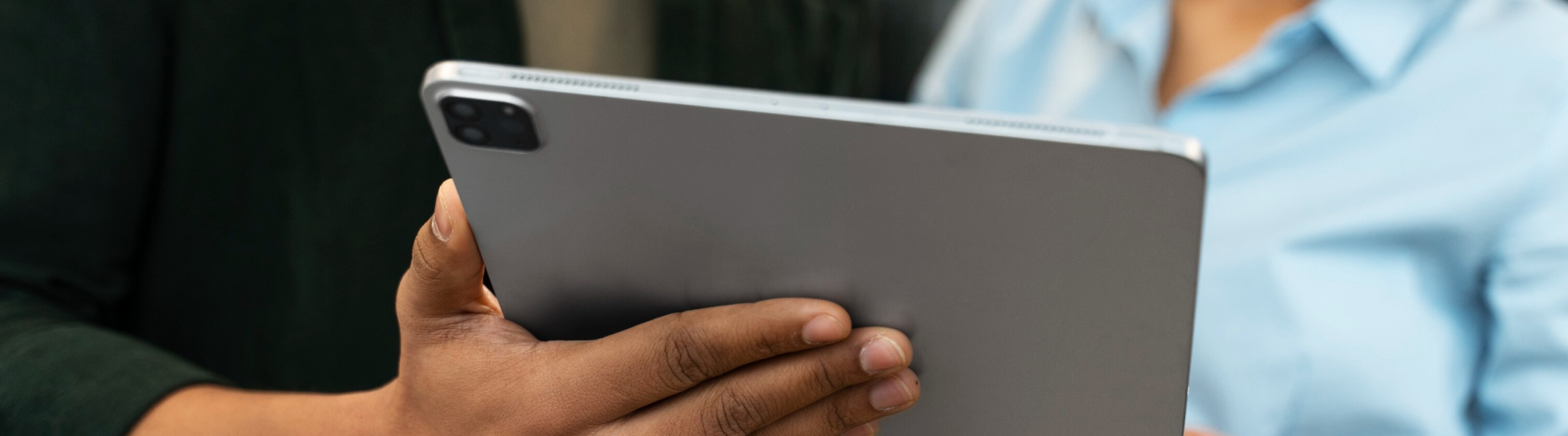 A man holding a tablet in his hand showing technology to a woman