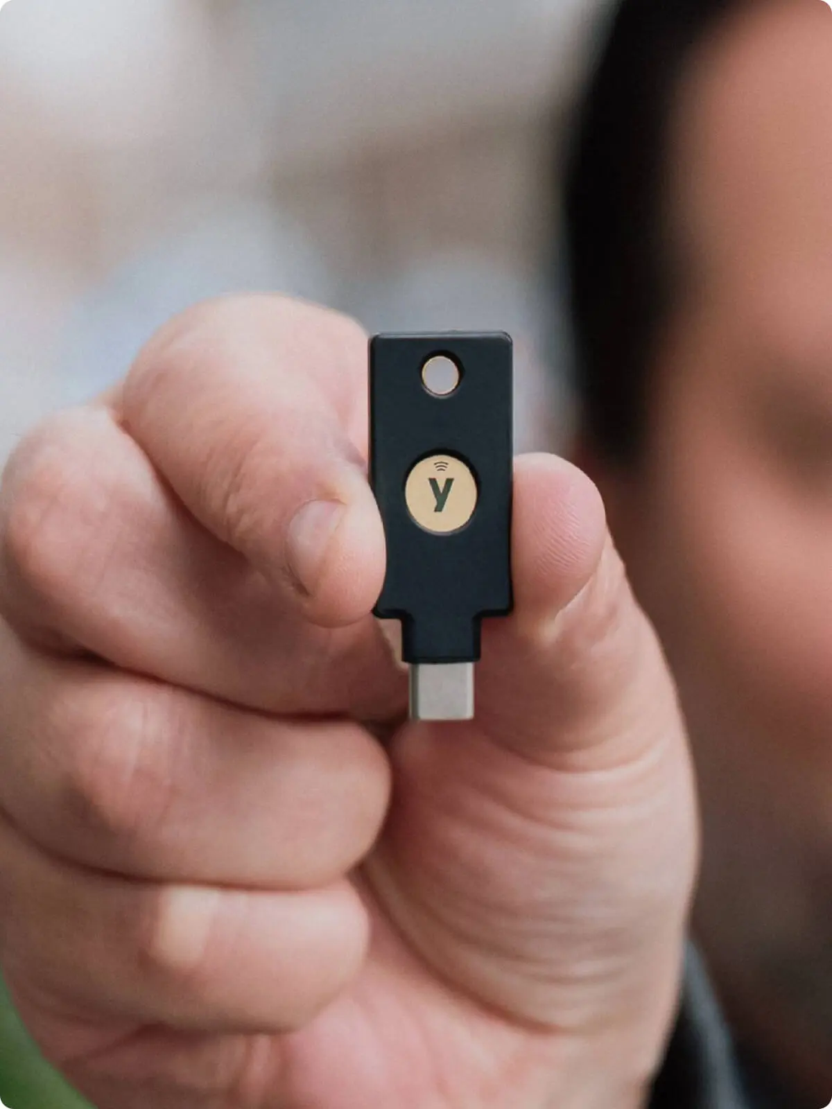 Close-up of a hand holding a YubiKey USB-C security key