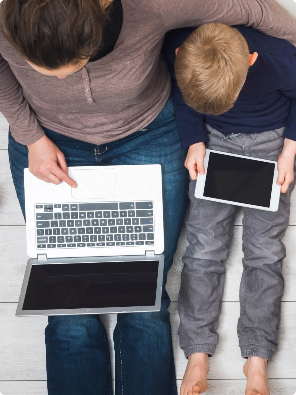 Overhead view of a parent and child sitting together, using a laptop and tablet