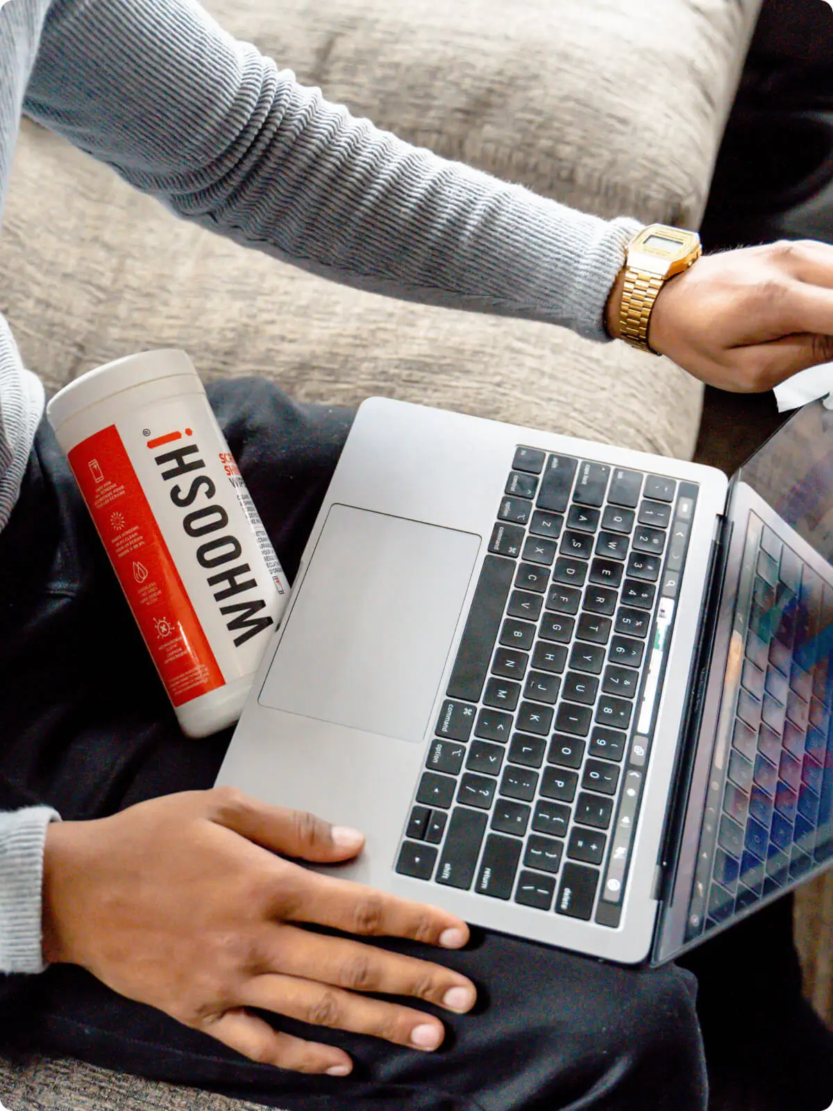 Overhead view of a laptop and WHOOSH screen cleaning wipes on someone's lap