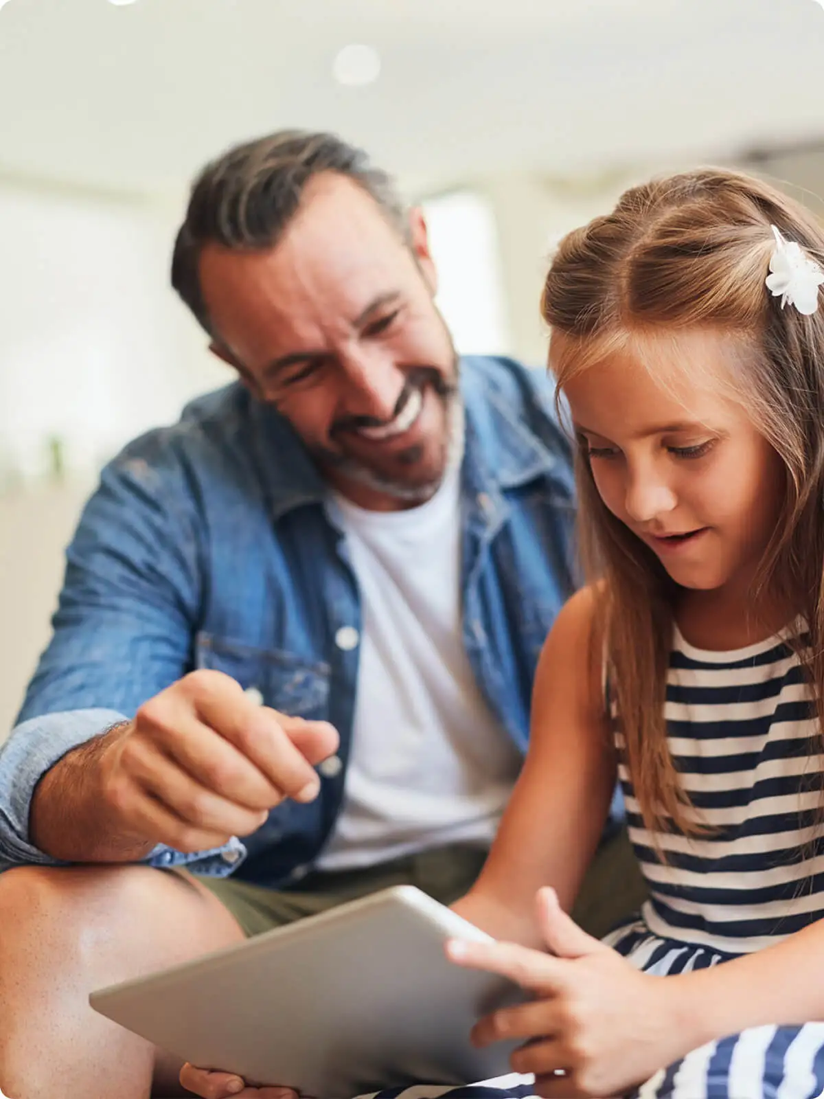 Father and daughter smiling while looking at a tablet together