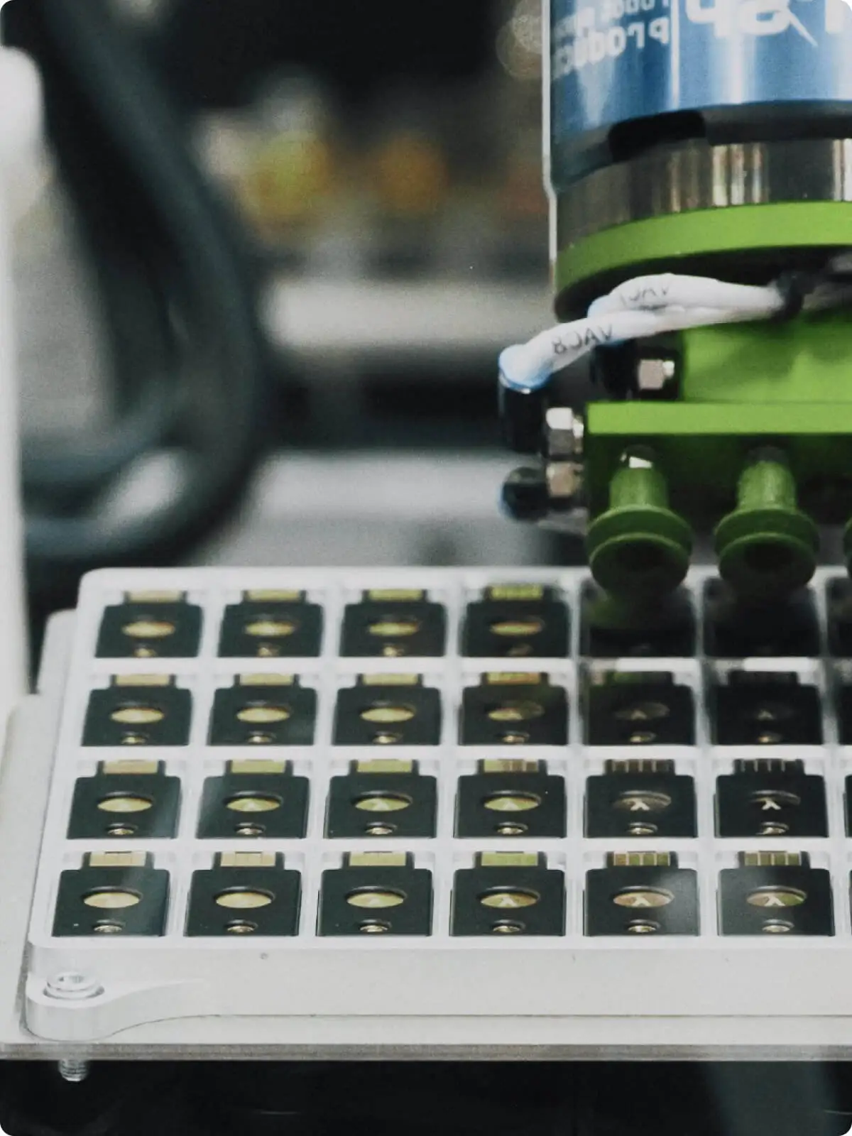 Close-up of automated manufacturing equipment assembling small security Yubikey components in a tray