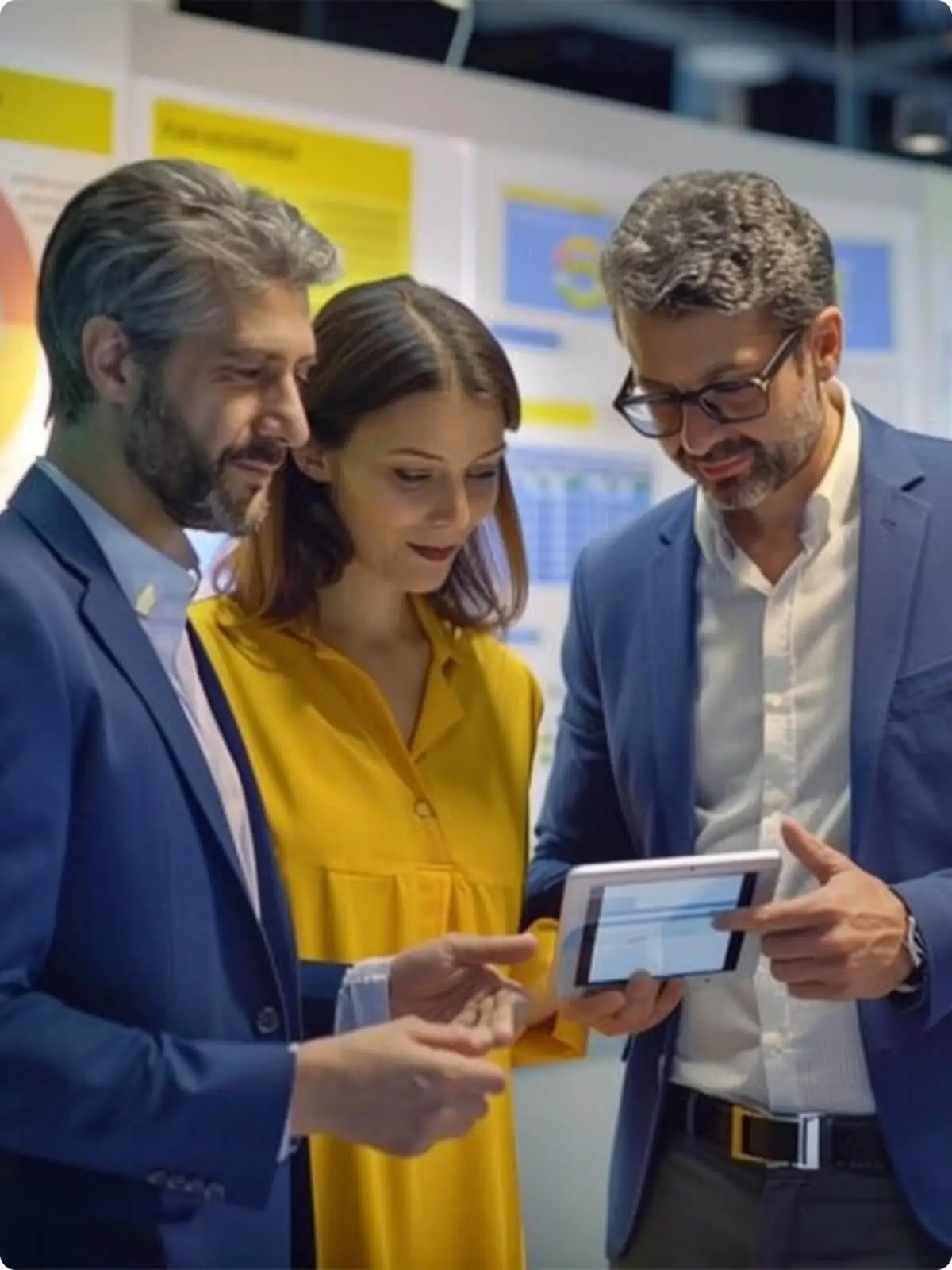 Three business professionals reviewing data together on a tablet